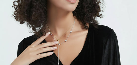 Woman wearing a black dress with a gold necklace against a white background
