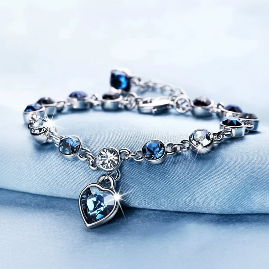 Silver bracelet with blue heart charm on a light blue background