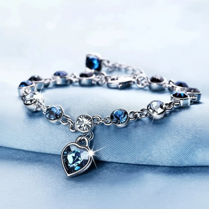 Silver bracelet with blue heart charm on a light blue background