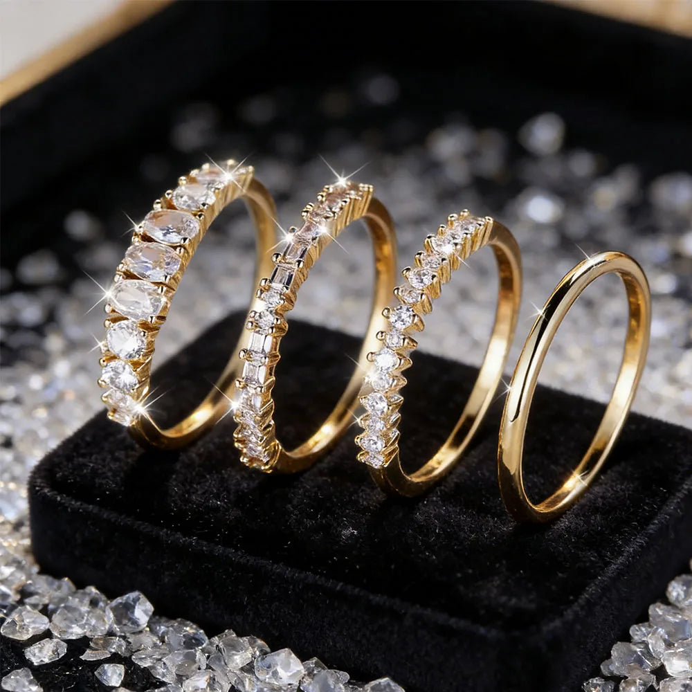 Gold rings with diamond accents on a black stand with scattered diamonds.