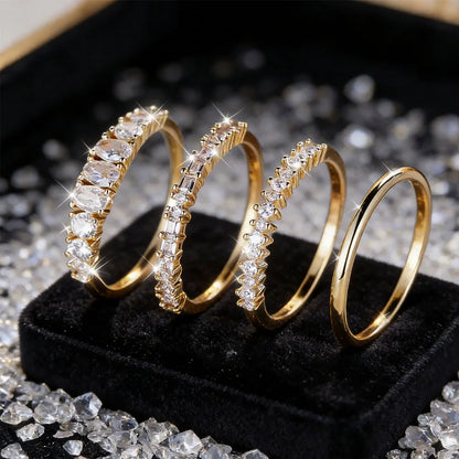 Gold rings with diamond accents on a black stand with scattered diamonds.